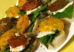 Delicious baked eggplant slices topped with greens, cheese, and roasted tomatoes.