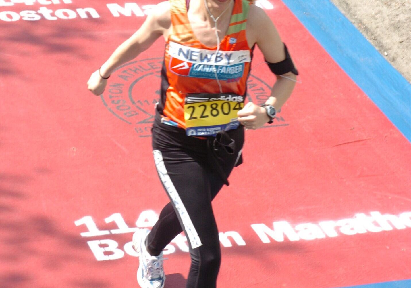 Runner crossing Boston Marathon finish line, celebrating achievement.