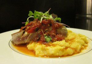 Gourmet sausage served on creamy polenta with microgreens.