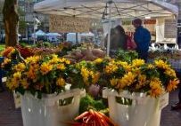 Outdoor market stall with vibrant flowers and peppers.