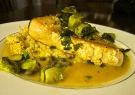 Close-up of a savory fish dish with sauce and garnished greens.