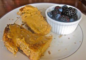 Peanut butter spread on toasted bread with a side of blackberries.