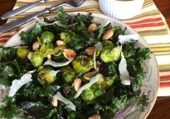 Plate of roasted Brussels sprouts with nuts and greens, served with a yellow sauce.