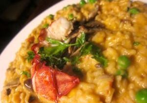 A creamy seafood risotto garnished with parsley and lobster.
