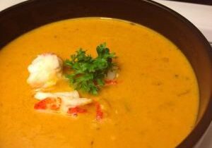 Creamy lobster bisque garnished with parsley and lobster claw.