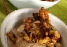 Ice cream topped with caramelized nuts in a white bowl.