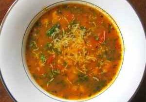 Bowl of vibrant vegetable soup with herbs and spices.