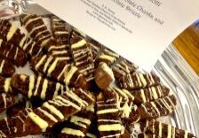 Plate of striped chocolate cookies with a nut on top and a card in the background.