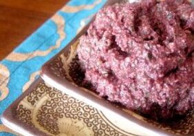A plate with a serving of purple sticky rice on a patterned cloth.