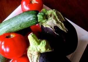 Fresh vegetables including tomatoes, zucchini, and eggplants.
