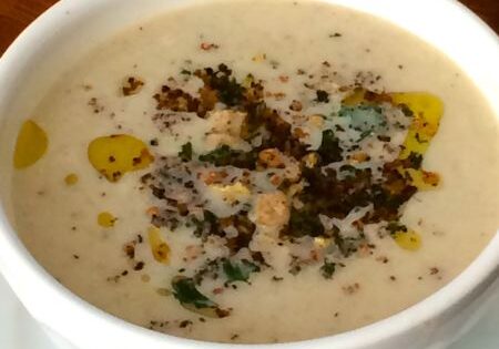 Creamy mushroom soup garnished with herbs and a drizzle of oil.