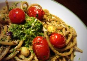 A plate of pasta with cherry tomatoes and herbs.