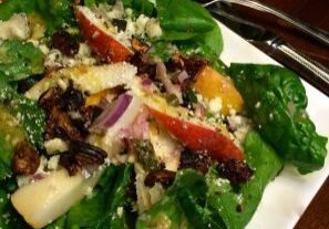 Fresh garden salad with mixed greens, fruits, and nuts.