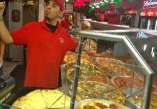 Pizza chef joyfully serving fresh pizzas behind the counter.