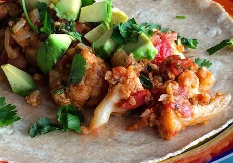 A colorful taco filled with vegetables and avocado on a vibrant plate.