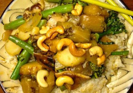 A plate of stir-fried vegetables with cashews over rice.