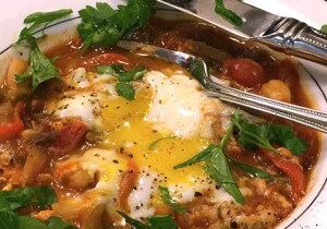 A delicious dish with eggs, tomatoes, and greens on a plate.