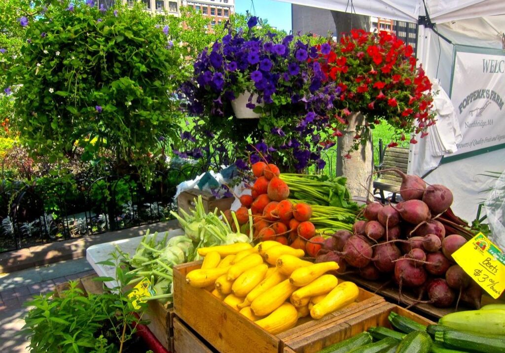 Colorful fresh fruits and flowers displayed at an outdoor market.