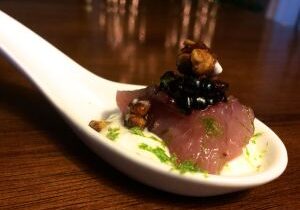 Elegant bite-sized tuna tartare appetizer with garnish on a ceramic spoon.