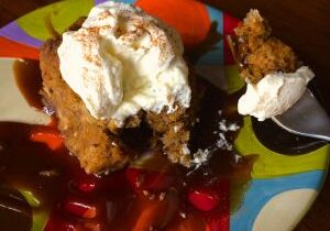 Fried dessert topped with whipped cream and syrup on a colorful plate.