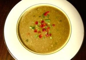 A bowl of lentil soup garnished with chopped green and red peppers.