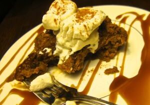 A decadent chocolate brownie topped with whipped cream and drizzled with chocolate sauce.