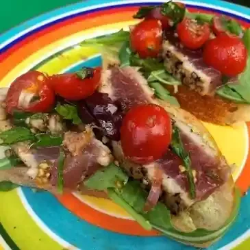 Tuna bruschetta with cherry tomatoes and greens.