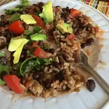 Rice, beans, avocado, and tomato on plate.