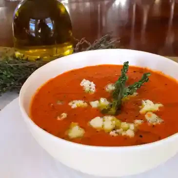 Tomato soup with herbs and cheese garnish.