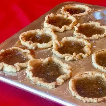 Homemade tarts on a metal baking tray.