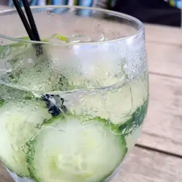 Glass of cucumber-infused drink with straws.