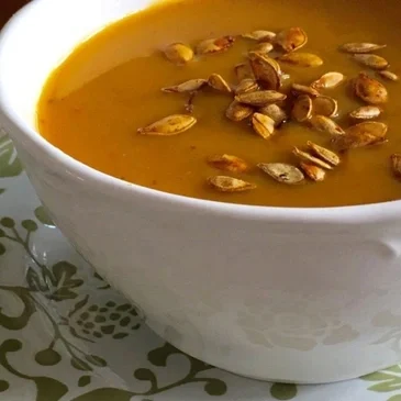 Pumpkin soup with roasted seeds in bowl.