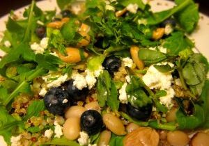 A colorful salad with chickpeas, olives, greens, and cheese.