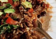 Plate of rice and beans with vegetables and avocado.
