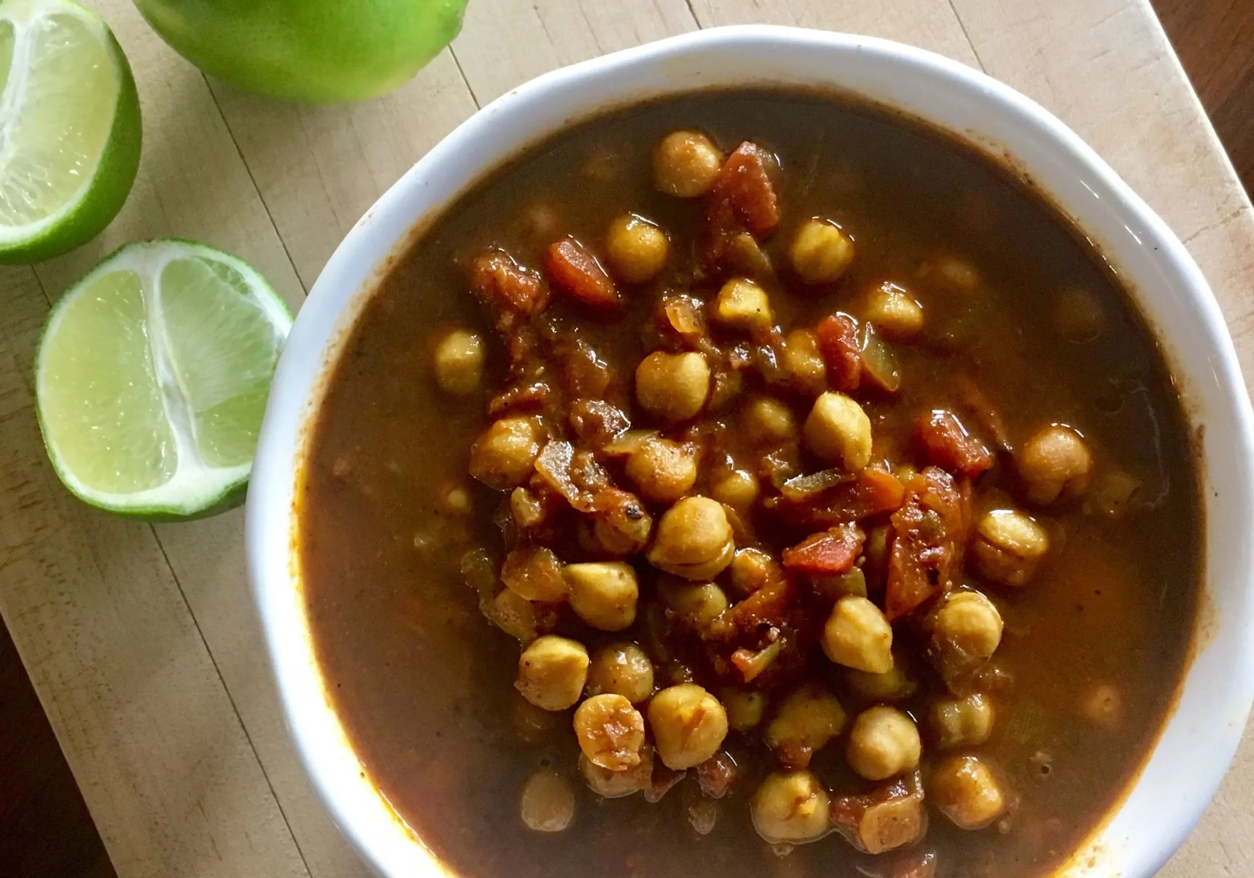 Chickpea stew with lime on wooden surface.