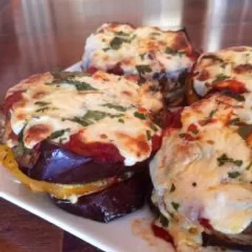 Cheesy eggplant stacks on white plate.