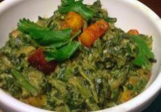 A bowl of green leafy vegetable curry with chickpeas and spices.