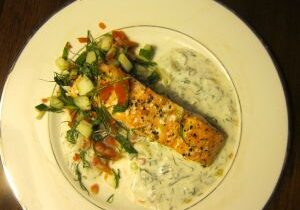 Grilled salmon served with creamy herb sauce and fresh vegetables.