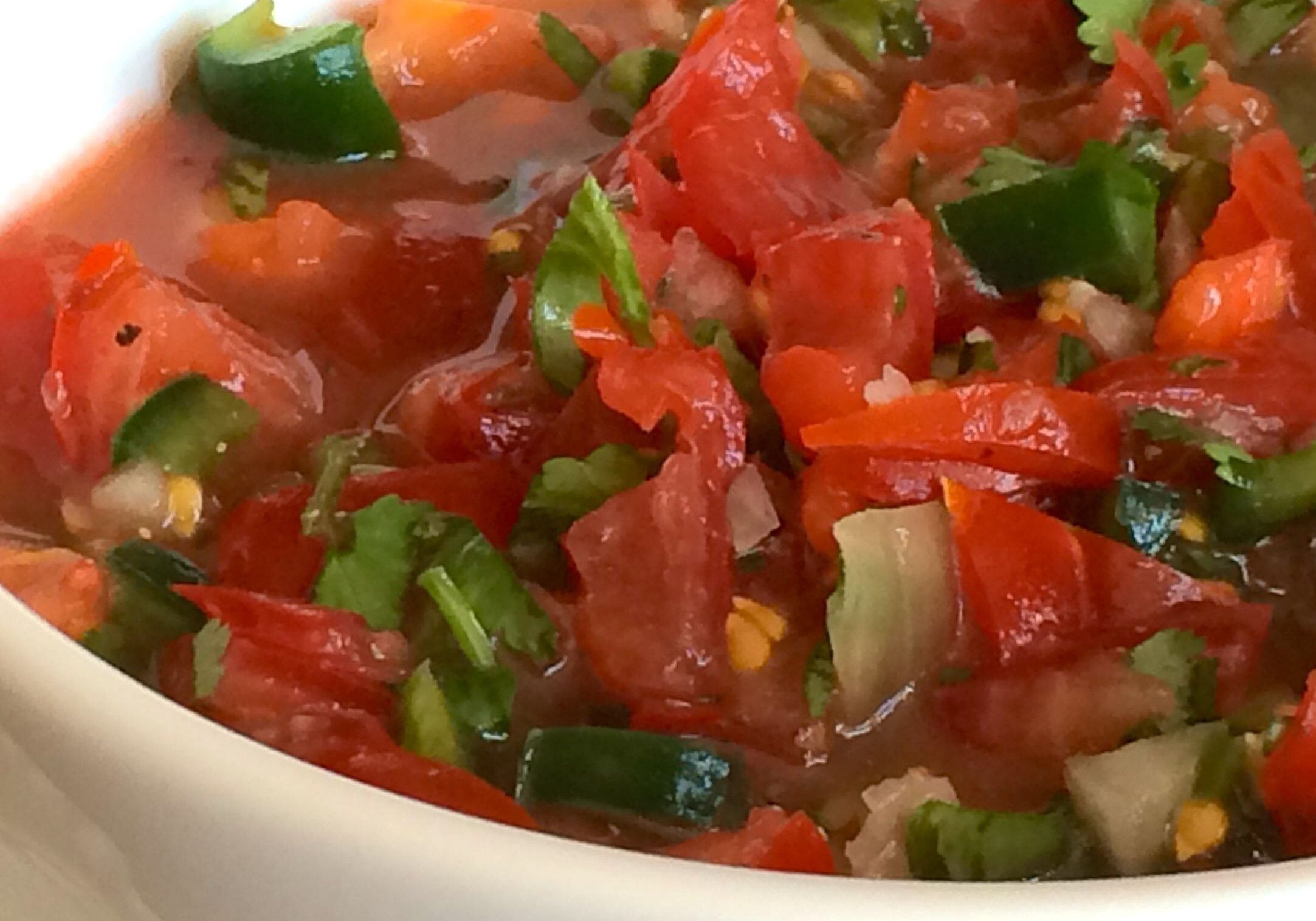 Fresh tomato salsa with herbs in a white bowl.