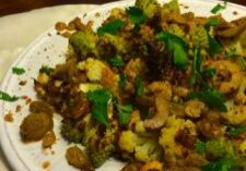 Plate of cooked mixed nuts garnished with fresh herbs.