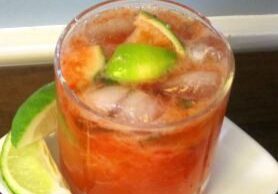 A refreshing cocktail with lime and ice in a glass.