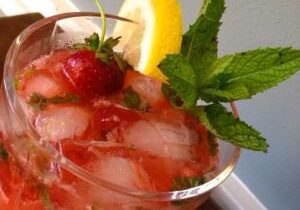 A refreshing strawberry cocktail garnished with mint and lemon.