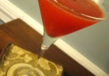 A vibrant red cocktail garnished with mint leaves and strawberries.