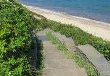 Concrete steps lead down to a sandy beach beside the ocean.