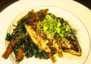 Grilled fish fillet served on a bed of sautéed greens and vegetables.