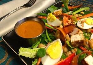 A vibrant salad with boiled eggs and dressing on the side.