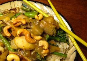 A plate of stir-fried vegetables with cashews and rice.