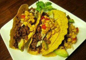 Three tacos filled with beef, chickpeas, and vegetables.