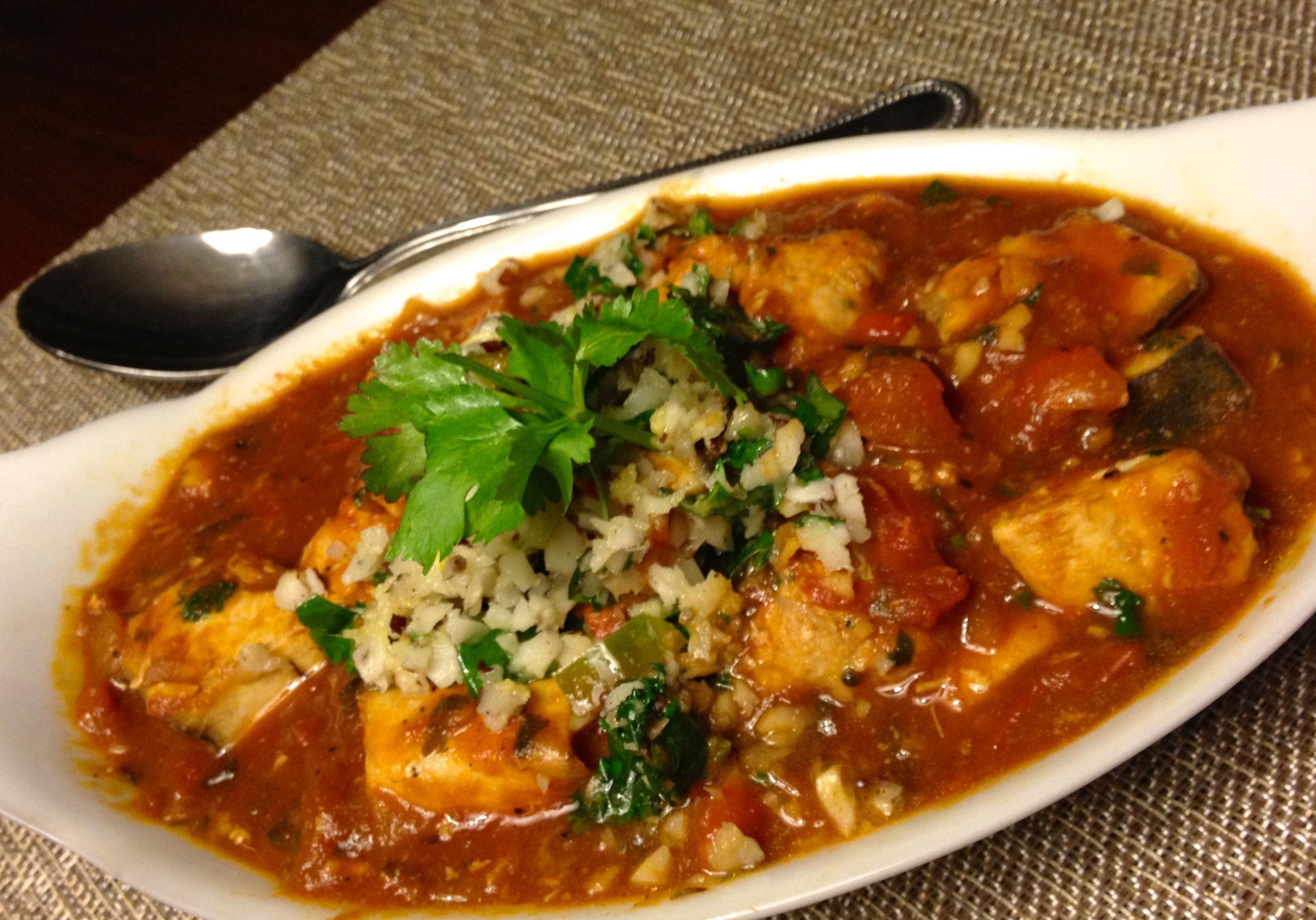 Spicy tofu curry garnished with fresh herbs and served in a white dish.