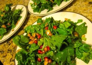 Fresh spinach salad with tomatoes and nuts on plates.